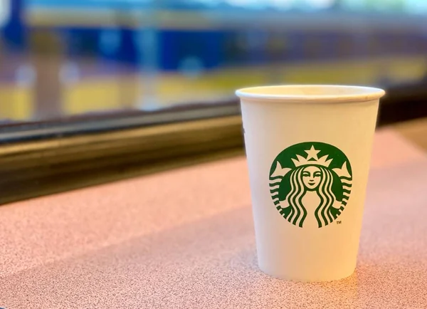 Caffè per andare a lavorare in treno. Starbucks in scatola di cartone. Stazione ferroviaria attraverso la finestra. — Foto Stock