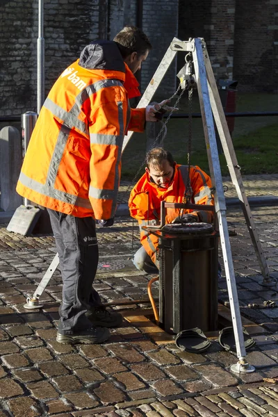 Technical workers repairing automatic bollards set in a cobble paved street