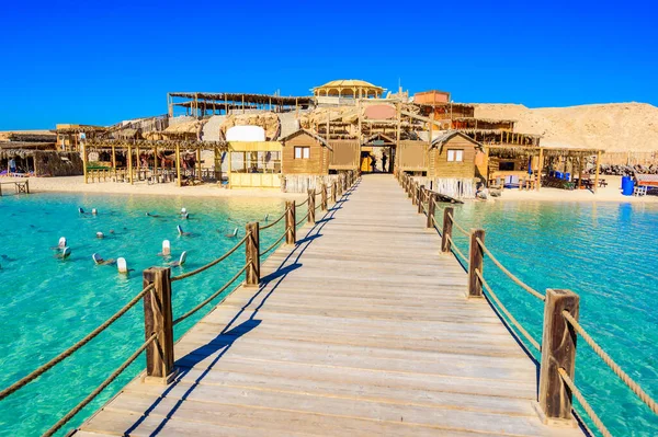 Wooden Pier at Orange Bay Beach with crystal clear azure water and white beach - paradise coastline of Giftun island, Mahmya, Hurghada, Red Sea, Egypt.