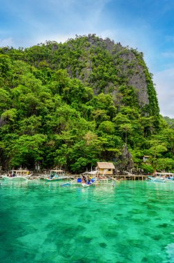 Coron adasındaki Kayangan Gölü 'ndeki ahşap rıhtımda teknelerle Cennet Koyu' nda mavi kristal su, tropikal seyahat yeri - Palawan, Filipinler.