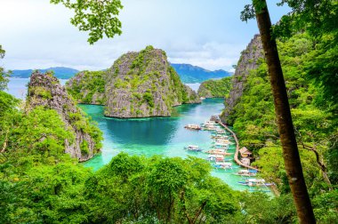 Filipinler, Palawan 'daki Coron Adası' ndaki Kayangan Gölü 'ndeki ahşap iskelede tekneleri olan Cennet Koyu' nda mavi kristal su..
