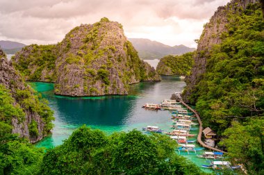 Blue crystal water in paradise Bay with boats on the wooden pier at Kayangan Lake in Coron island, Palawan, Philippines. clipart