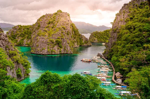 Filipinler, Palawan 'daki Coron Adası' ndaki Kayangan Gölü 'ndeki ahşap iskelede tekneleri olan Cennet Koyu' nda mavi kristal su..