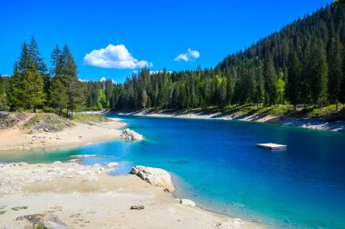 Small island in the middle of Cauma Lake (Caumasee) with crystal blue water in beautiful mountain landscape scenery at Flims, Graubuenden - Switzerland