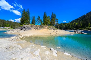 Small island in the middle of Cauma Lake (Caumasee) with crystal blue water in beautiful mountain landscape scenery at Flims, Graubuenden - Switzerland