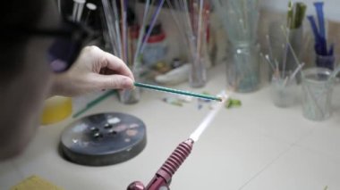 Usta 4K ocağının alevinin üzerine cam bir çubuk fırlattı.