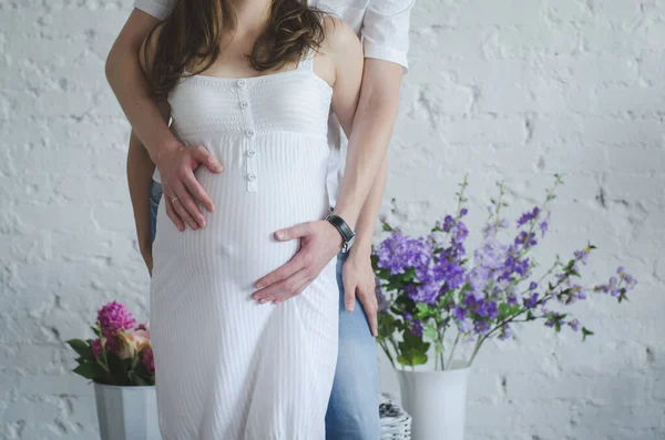 Man hugs the belly of a pregnant woman