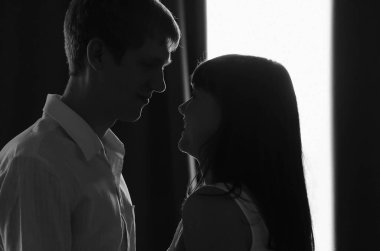 Kız ve erkek birbirine bakar, birbirine aşık çift, arka planda siyah beyaz siluet