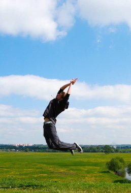 Gökyüzüne, tarlaya, gündüze karşı atlayan genç adam