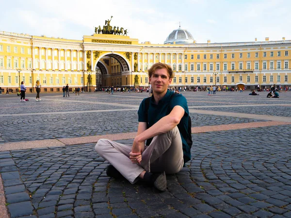 St. Petersburg 'daki saray meydanında genç bir adam oturuyor, yaz günü.
