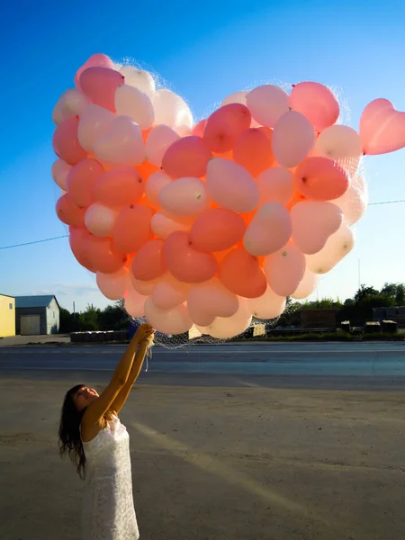 Güzel genç bir kadın elinde bir sürü balon tutuyor.