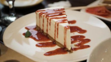 Beyaz tabakta reçelli cheesecake, restoranda tatlı.