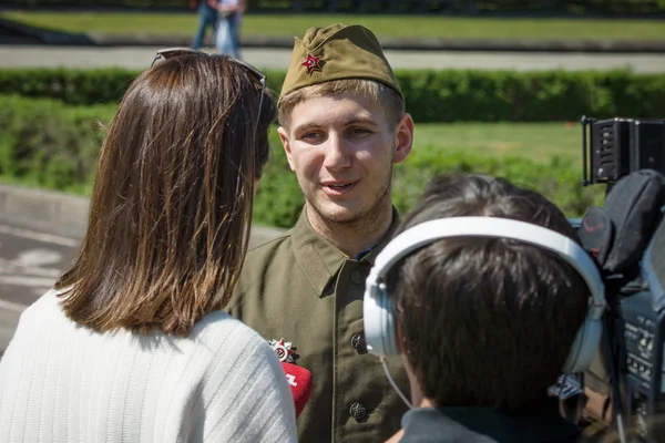 Journalist Ukrainian TV station 1+1 is interviewing a young man dressed in the form of a Soviet soldier during the war. — Stock Photo, Image