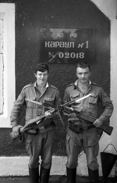 A soldiers posing with guns. The inscription in Russian: Russian Defence Ministry. Guard 1, the number of military unit 02018. Film scan. Large grain — Stock Photo, Image