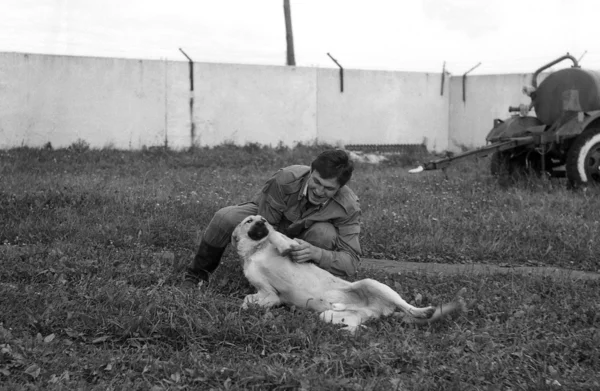Ένας στρατιώτης που παίζει με ένα σκυλί. σάρωση φιλμ. μεγάλος κόκκος — Φωτογραφία Αρχείου