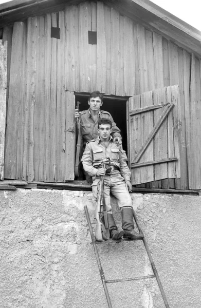 Zwei Soldaten posieren mit Gewehren auf dem Dachboden eines alten Hauses. Filmscan. Großkorn — Stockfoto
