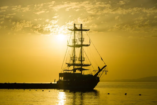 Sunset over the sea and a lone sailboat in the bay. — Stock Photo, Image