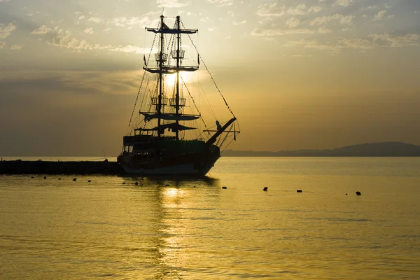 Západ slunce nad mořem a osamělý plachetnice v zátoce. — Stock fotografie