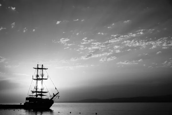 Sunset over the sea and a lone sailboat in the bay. Stylization. Black and white. — Stock Photo, Image