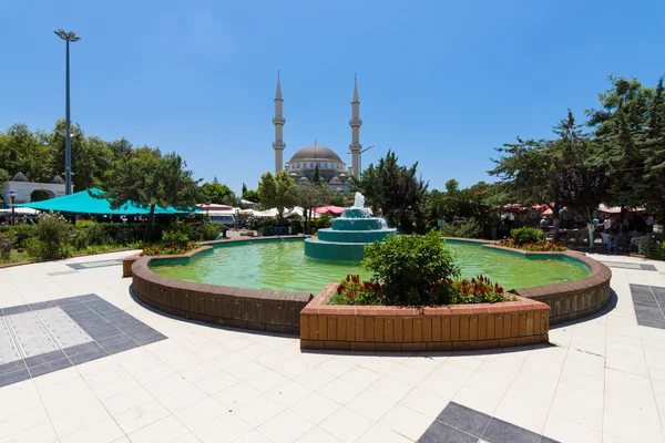 La place centrale avec une fontaine dans le village. En arrière-plan Mosquée — Photo