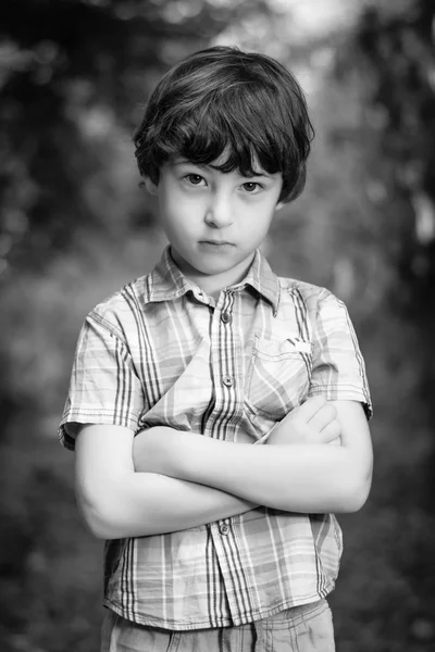 Retrato de menino sério com os braços dobrados. Preto e branco . — Fotografia de Stock