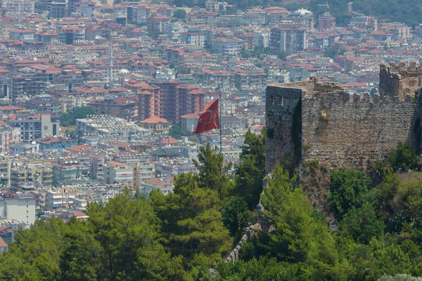 Den turkiska flaggan på bakgrund av husen i det centrala distriktet Alanya. Visa från den gamla fästningen i Alanya. — Stockfoto