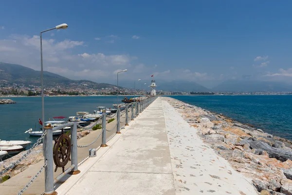 O farol e o longo cais na entrada do porto marítimo de Alanya — Fotografia de Stock