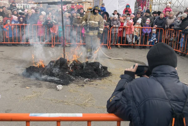 Brandweerman blust beeltenissen Maslenitsa. — Stockfoto