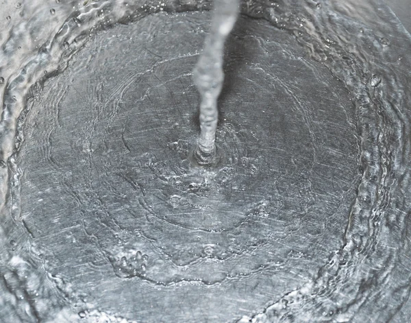 Agua que fluye por el agujero en un fregadero de cocina . — Foto de Stock