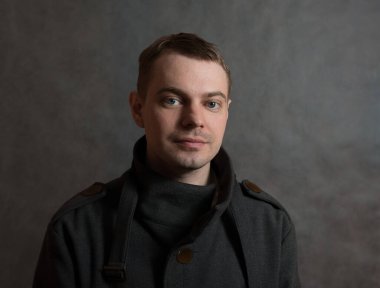 Siyah arka planda ceketli genç bir adam..