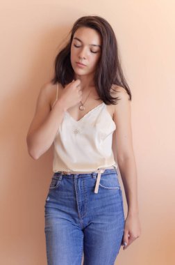 Bej duvar arkasında poz veren güzel genç bir kadın..