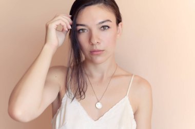 Bej duvar arkasında poz veren güzel genç bir kadın..