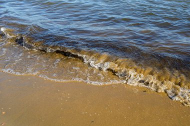 Gün batımında deniz kıyısında dalgalar. Sığ alan derinliğine sahip seçici odak.