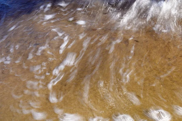 Deniz kıyısındaki dalgalar yavaş bir deklanşör hızıyla yakalanır. Doğal soyut hareket arkaplanı.