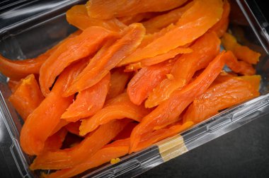 Koyu arkaplanda plastik bir kutuda kurutulmuş mango. Seçici odak.