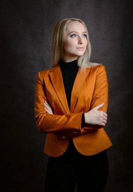 Turuncu ceketli güzel bir genç kadının portresi. Stüdyo çekimi.