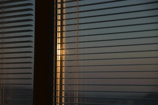 The sun shines through the blinds. Selective focus.