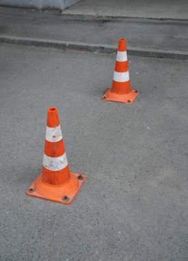 Asfalt yüzeyinde iki trafik konisi.