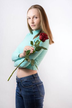 Kadın arka planda kırmızı bir gül tutuyor..