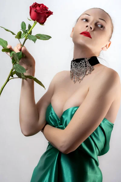 Женщина Зеленом Платье Держит Одну Красную Розу Руке Светлом Фоне — стоковое фото
