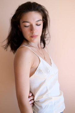 Bej duvar arkasında poz veren güzel genç bir kadın..