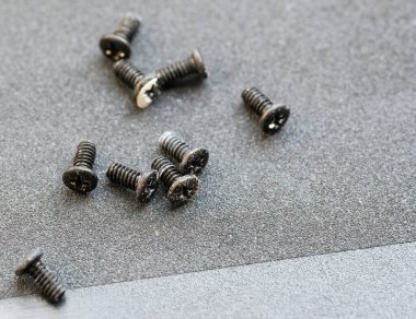 Gri arka planda küçük metalik vidalar.