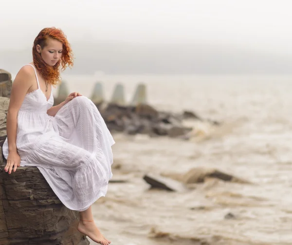 Kvinna sitter på kusten vid stranden. — Stockfoto