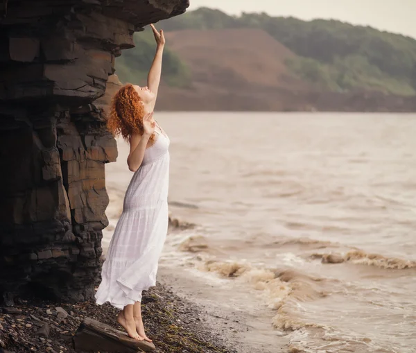 Frau in weißem Kleid steht am Strand. — Stockfoto