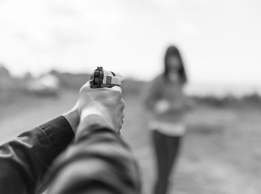 Adam el silah amaç kadına tutarak.