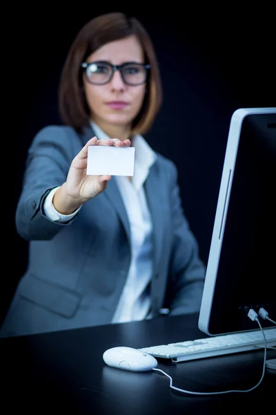 Woman works at the computer and showing a blank card — Stock Photo, Image