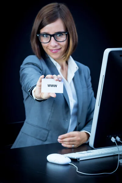 Woman works at the computer and showing a card with text — Stock Photo, Image