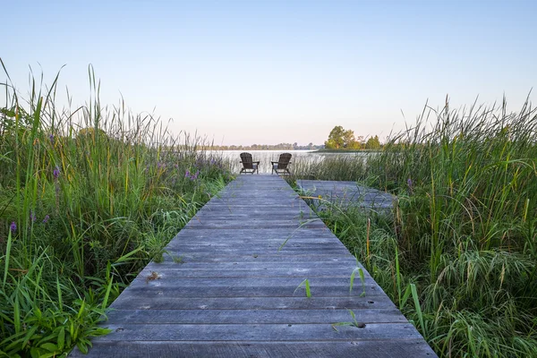 Due sedie Adirondack alla fine di una passerella e in riva al lago — Foto Stock