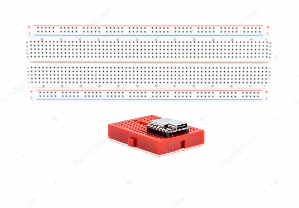 Small Red Electronic Breadboard and a Computer Controller Chip Isolated on White Background