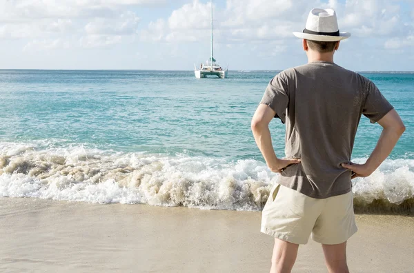 Bakifrån av en Man i vit hatt står på en strand — Stockfoto